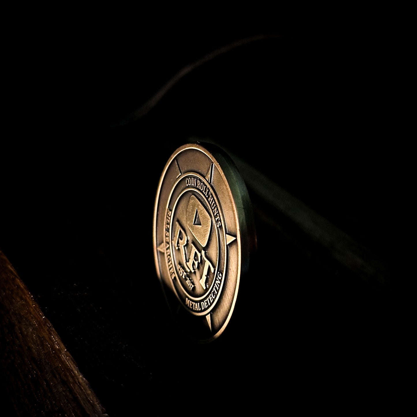 Rob Finds Treasure OG OLD LOGO Bronze Challenge Coin with background, side edge view